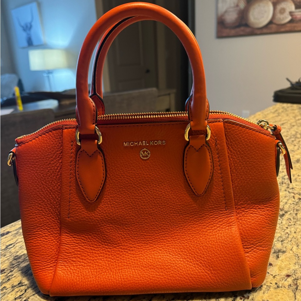 Orange Michael Michael Kors handbag with crossbody straps and key strap.
